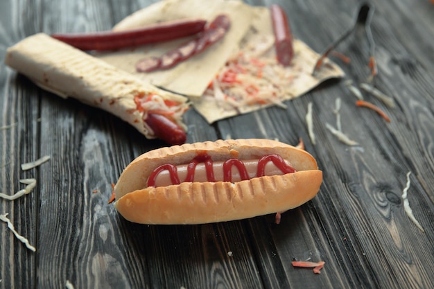 Cachorros-quentes e pratos de fast food em fundo de madeira