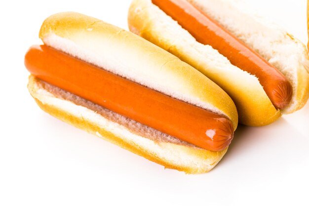 Cachorros-quentes tradicionais em um pão de cachorro-quente branco sobre um fundo branco.