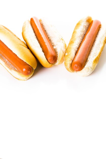 Cachorros-quentes tradicionais em um pão de cachorro-quente branco sobre um fundo branco.