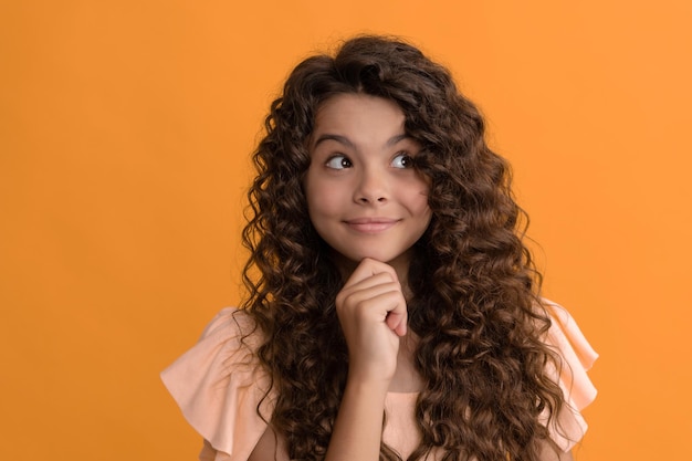 Cachos de cabelo crespo. menina tem penteado ondulado. retrato de criança de frizz. expressar emoção positiva. cuidados com o cabelo e com a pele. cabeleireiro. pensando garoto com cabelo encaracolado. penteado de beleza adolescente. modelo de moda feminina