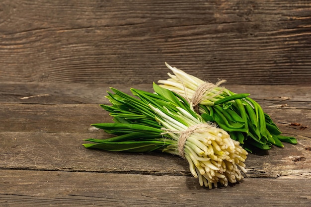 Cachos de colheita fresca de primavera ramson alho-poró selvagem folhas picantes perfumadas na mesa de madeira vintage