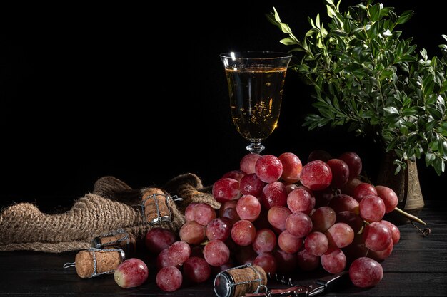 Cachos de uvas-de-rosa e maçãs verdes em uma superfície escura. ainda vida.