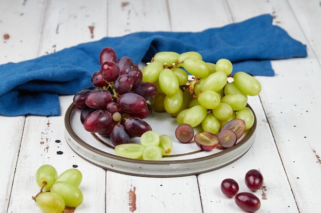 Foto cachos de uvas verdes e vermelhas maduras frescas em uma mesa de madeira