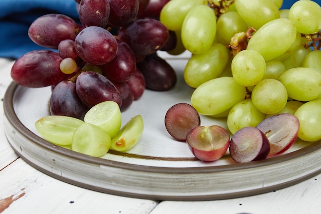 Cachos de uvas verdes e vermelhas maduras frescas em uma mesa de madeira