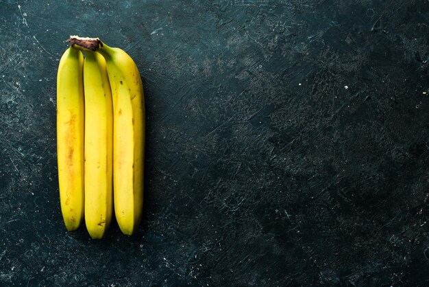 Cachos tropicais de bananas amarelas em um fundo de pedra preta Vista superior