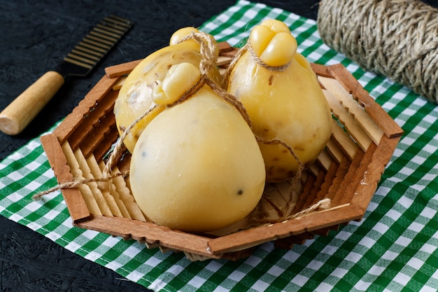 Caciocavallo do queijo em uma cesta em um fundo preto. Pêra de queijo