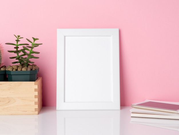 Cacto branco em branco do quadro e da planta em uma tabela branca contra a cópia cor-de-rosa da parede. Maquete com espaço de cópia.