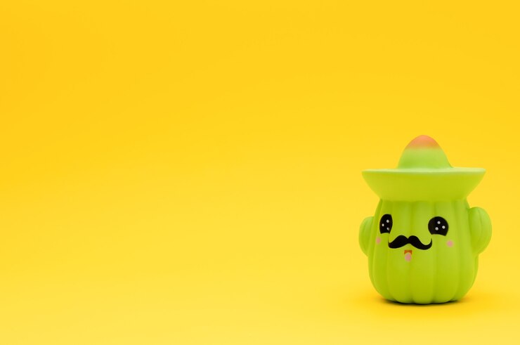 Foto cacto de brinquedo em sombrero em fundo amarelo com espaço de cópia