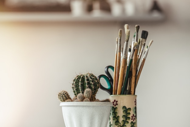 Foto cactus em vaso de flores brancas e conjunto de pincéis para pintura.