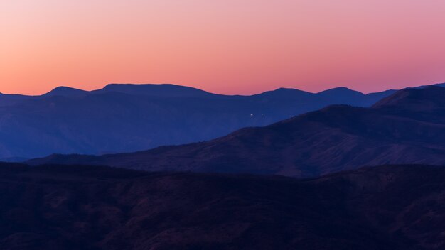 Cadeia de montanhas recortada após o pôr do sol