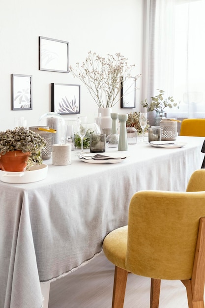 Cadeira amarela na mesa com talheres no interior da sala de jantar brilhante com flores e cartazes Foto real