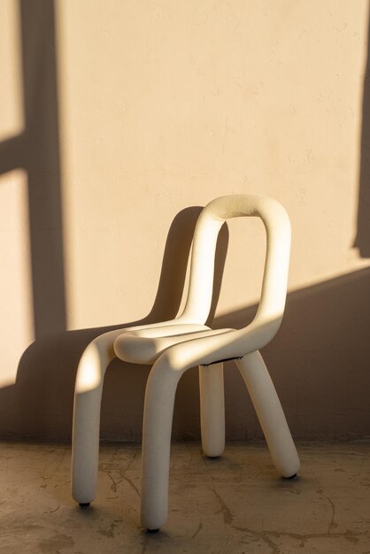 Foto cadeira da moda em um piso de concreto em frente à parede marrom luz solar do pôr do sol interior minimalista