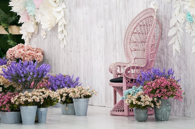 Cadeira de bambu vintage de luxo frente ao pano de fundo de madeira branca e muitas flores ao redor