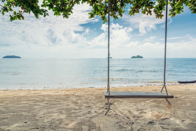 Foto cadeira de madeira do balanço que pendura na árvore perto da praia na ilha em phuket, tailândia.