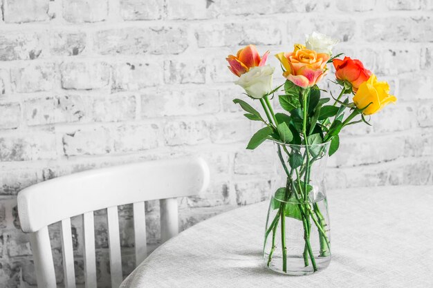 Cadeira de madeira rústica na mesa um vaso com um buquê de rosas em uma sala brilhante Casa aconchegante