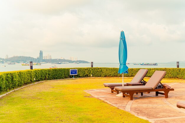 cadeira de piscina ou piscina com cama e guarda-sol ao redor da piscina com fundo de praia do mar em Pattaya, na Tailândia