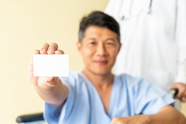 Cadeira de rodas paciente sênior asiática sorrindo com cartão de crédito