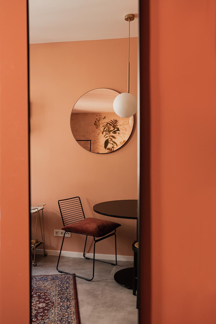 Cadeira elegante, elegante, mesa, espelho, tapete, paredes coloridas de coral, estética moderna, minimalista, design de interiores de sala de estar, interiores de apartamento de luxo.