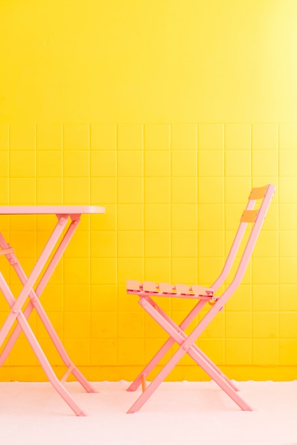 cadeira rosa vazia e mesa com parede amarela