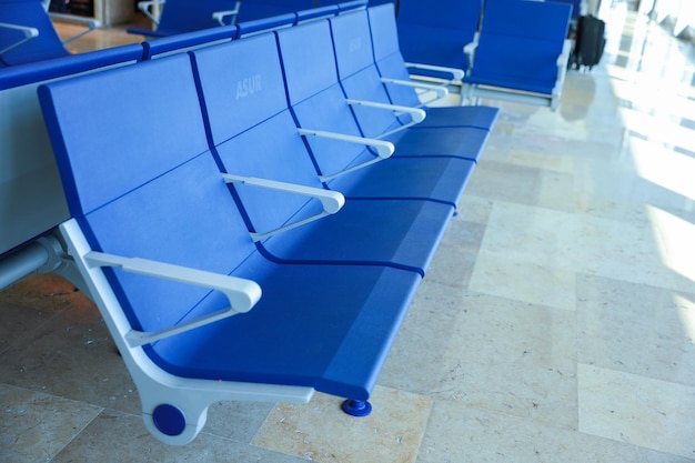 Foto cadeiras azuis em uma sala de espera com a palavra avião ao lado.