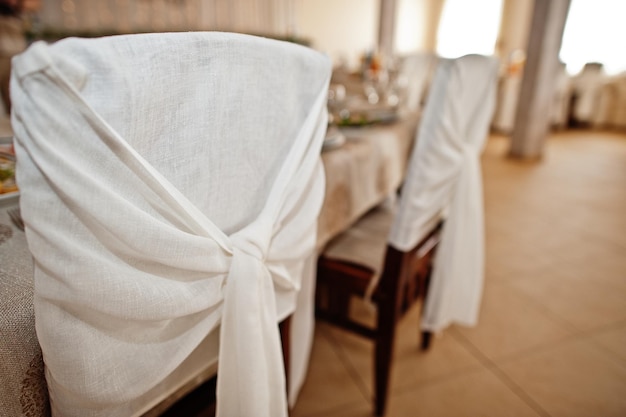 Cadeiras com fitas brancas na mesa de casamento no restaurante