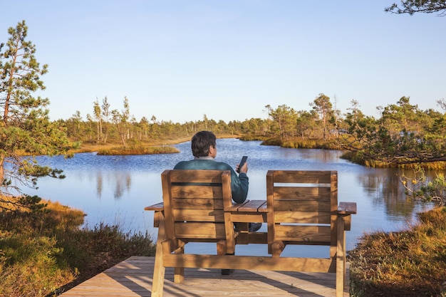 Cadeiras de madeira ou bancos de descanso confortáveis no terraço de madeira na costa da lagoa do pântano paisagem escandinava Letónia