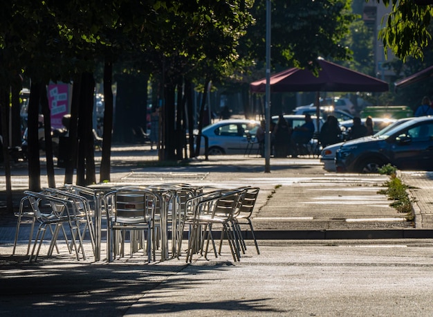 Cadeiras de metal vazias em um terraço de rua em um bar da cidade ao pôr do sol.