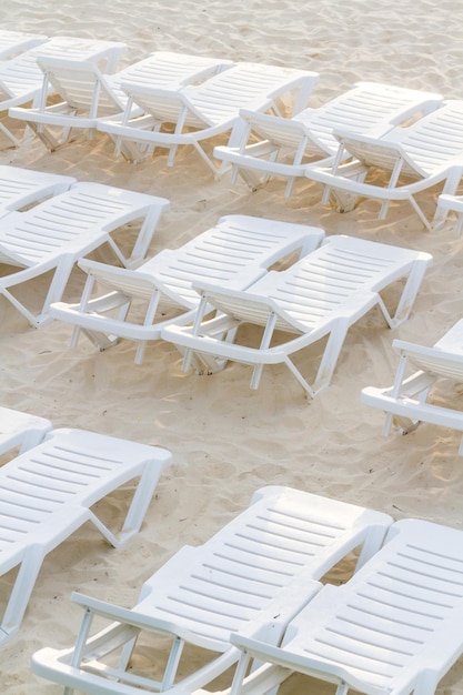 Cadeiras de piscina brancas na praia.