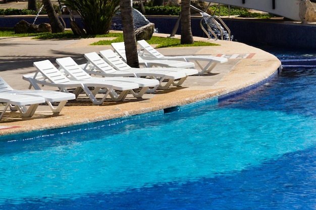 Cadeiras de piscina de plástico brancas na piscina.