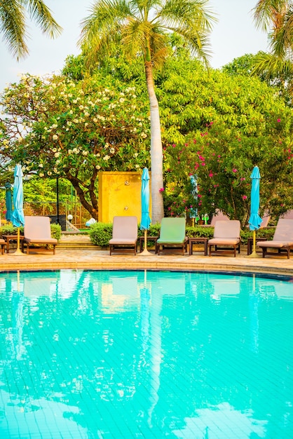 Foto cadeiras de piscina e guarda-sol ao redor de piscina com coqueiro