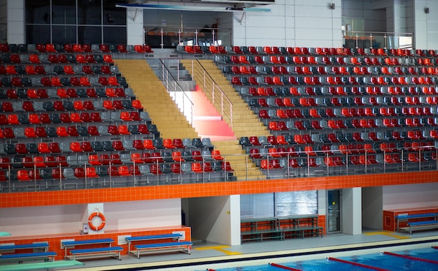 Cadeiras de plástico em arquibancada vazias em uma grande piscina esportiva para natação e mergulho