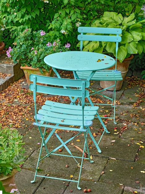 Foto cadeiras e mesa de metal de pátio verde em um quintal privado sereno e luxuriante em casa em um dia de verão conjunto de móveis de pátio sentado em jardim vazio e tranquilo com flores e plantas frescas