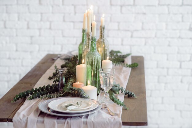 cadeiras e mesa para convidados, decoradas com velas, servidas com talheres e louças e cobertas com uma toalha de mesa.