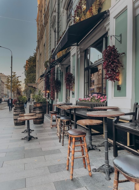 Foto cadeiras e mesas vazias em um café de calçada no meio de edifícios na cidade