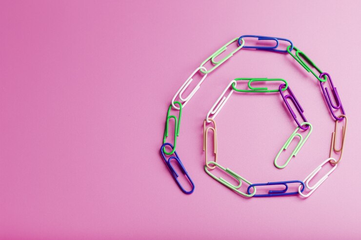 Foto una cadena de clips de papel multicolores sobre un fondo rosa. concepto de cooperación y comunicación empresarial