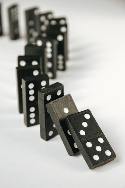 Cadena de dominó negro sobre fondo blanco de mesa