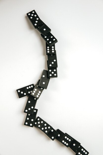 Cadena de dominó negro sobre un fondo de mesa blanco Concepto de efecto dominó