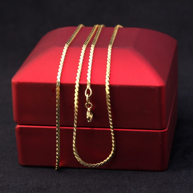 Cadena de joyas de oro en una caja de regalo roja.