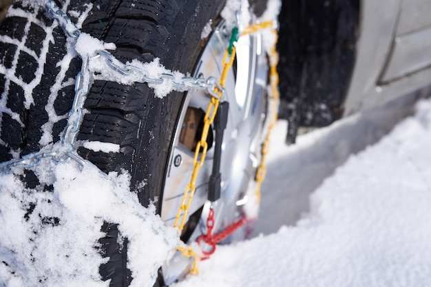 Cadena de nieve sobre una rueda en nieve profunda en invierno