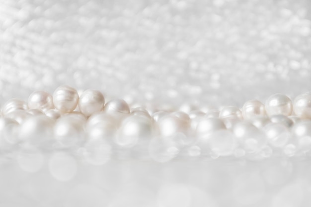 Foto cadena de perlas blancas naturales sobre un fondo brillante en un enfoque suave con reflejos