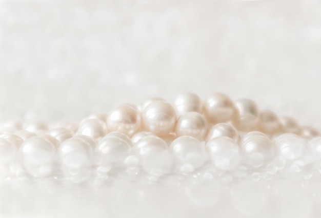 Cadena de perlas blancas de la naturaleza sobre un fondo brillante en un enfoque suave, con reflejos