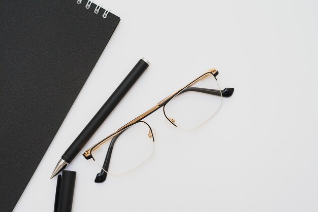 Caderno aberto com caneta e óculos isolados