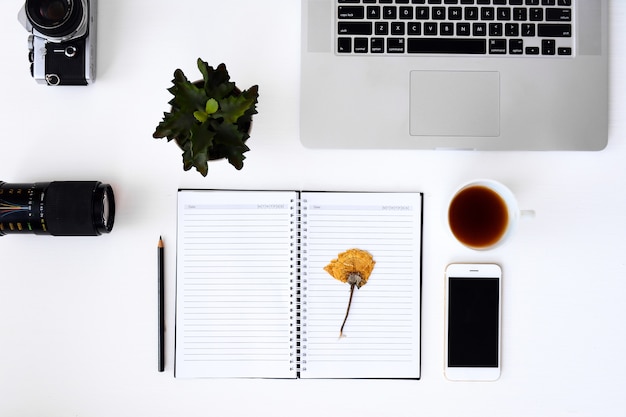 Caderno aberto com páginas em branco de flor, laptop, câmera, lente