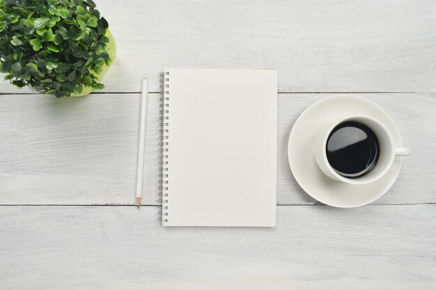 Caderno aberto em branco com café no espaço de madeira.