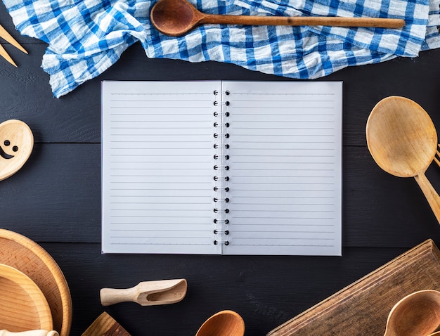 Caderno aberto em branco em linha e acessórios de cozinha de madeira