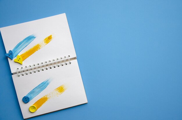 Caderno aberto horizontal flatlay com traços amarelos e azuis sobre fundo azul