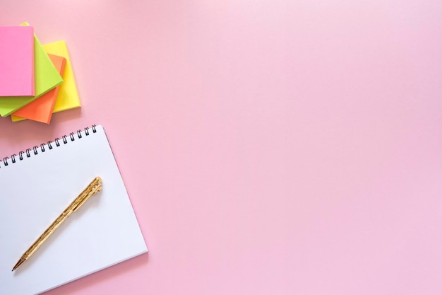 Caderno com caneta dourada e sobreposição de pilha de adesivos