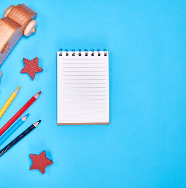 caderno com folhas brancas em linha e lápis de madeira multicoloridos