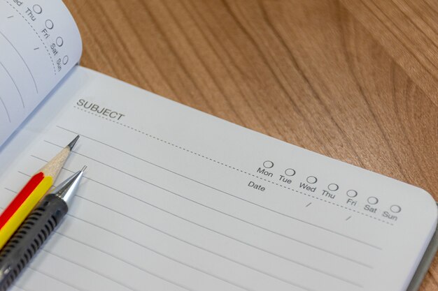 Caderno com lápis e caneta na mesa