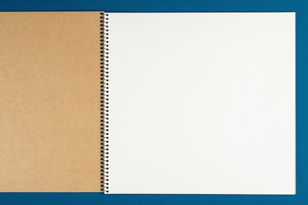 Caderno com lápis na vista superior da parede azul, estudante fazendo lição de casa, mesa de trabalho de escritório plana leigos. bloco de notas vazio na mesa